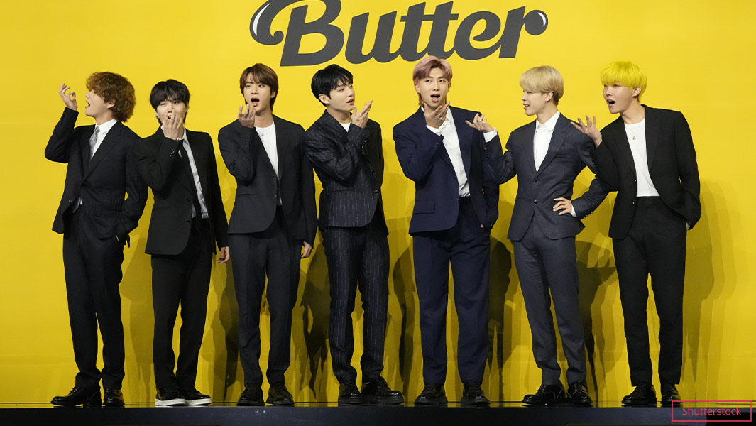 BTS making fun faces wearing suits in front of Butter sign